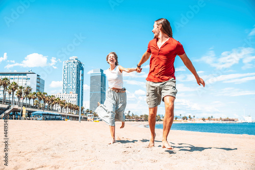 Happy couple in love enjoying vacation running on tropical beach - Boyfriend and girlfriend having fun outdoor on summer holiday - Vacations and lifestyle concept photo