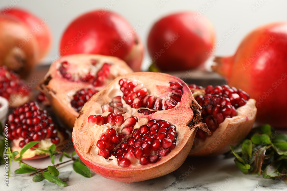 Delicious ripe pomegranates on white table, closeup Delicious ripe pomegranates on white table, closeup