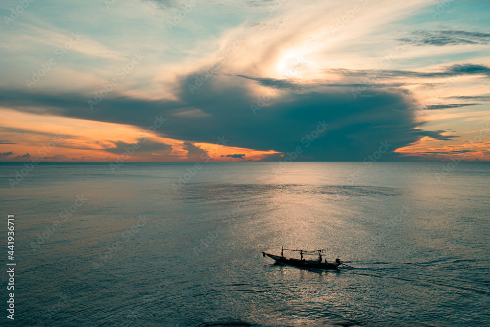 Long tail fishing boat sailing on the sea at sunrise