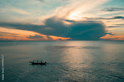 Long tail fishing boat sailing on the sea at sunrise