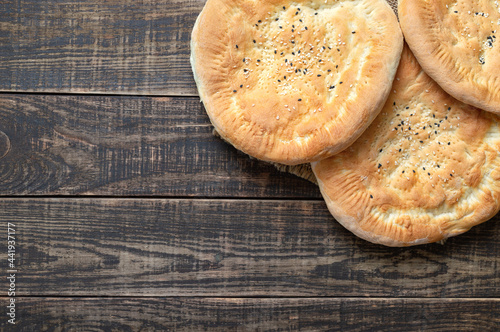 Round unleavened tortillas on a wooden background. Simple rustic sesame bread. Top view, flat lay, copy space. photo