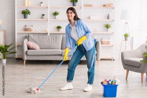 Portrait of woman cleaning floor with string mop