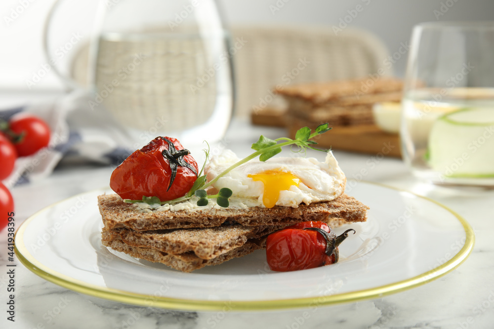 Fresh rye crispbreads with poached egg, cream cheese and grilled tomatoes on white marble table, closeup Fresh rye crispbreads with poached egg, cream cheese and grilled tomatoes on white marble table, closeup