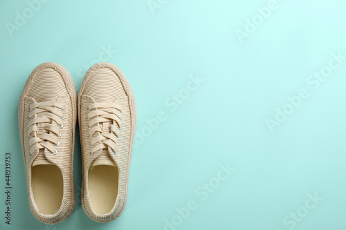Pair of stylish comfortable shoes on turquoise background, flat lay. Space for text