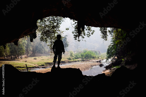 people standing at the entrance to the cave. Outside there are streams and trees.