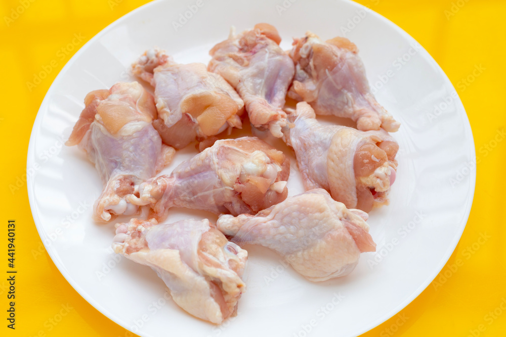 Fresh raw chicken wings (wingstick) in white plate on yellow background. Fresh raw chicken wings (wingstick) in white plate on yellow background.