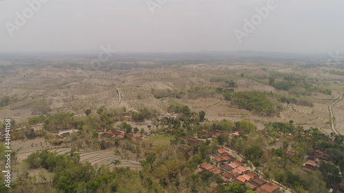 agricultural land in rural areas with farmlands, fields with crops, trees in arid hilly terrain. aerial view growing crops in asia in hilly areas Indonesia.