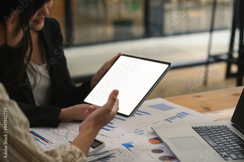 Closed up with businesswomen and businessman discussing about business ideas while gathering at table with document paper and blank scree of digital tablet, co working.