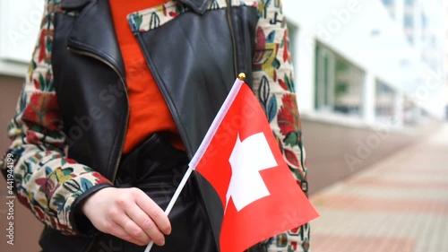 Unrecognizable woman holding Swiss flag. Girl walking down street with national flag of Switzerland photo
