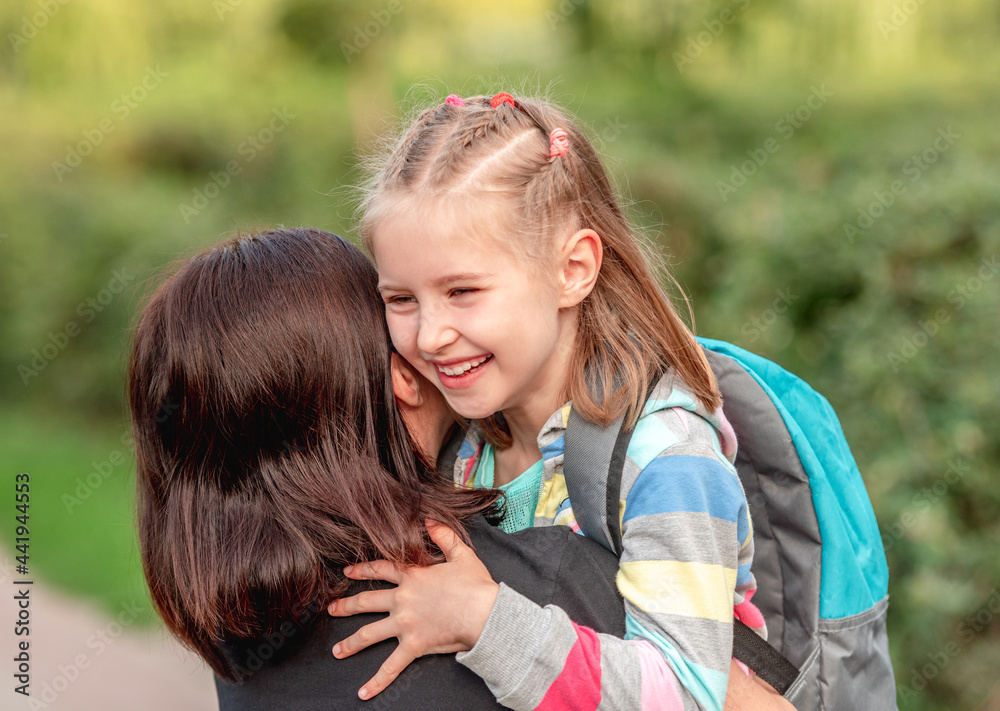 Fototapeta premium School girl hugging mother after classes