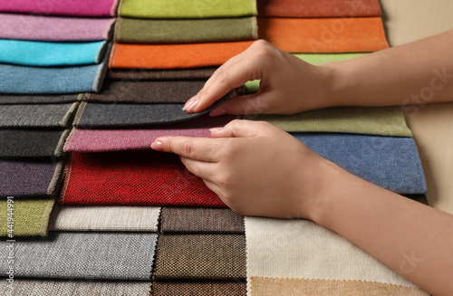 Woman choosing fabric among multicolored samples  closeup