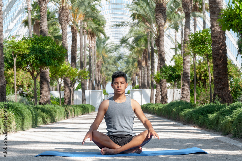 Fototapeta premium latin man meditating with tropical background