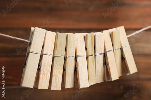 Many clothespins on rope against wooden background, closeup