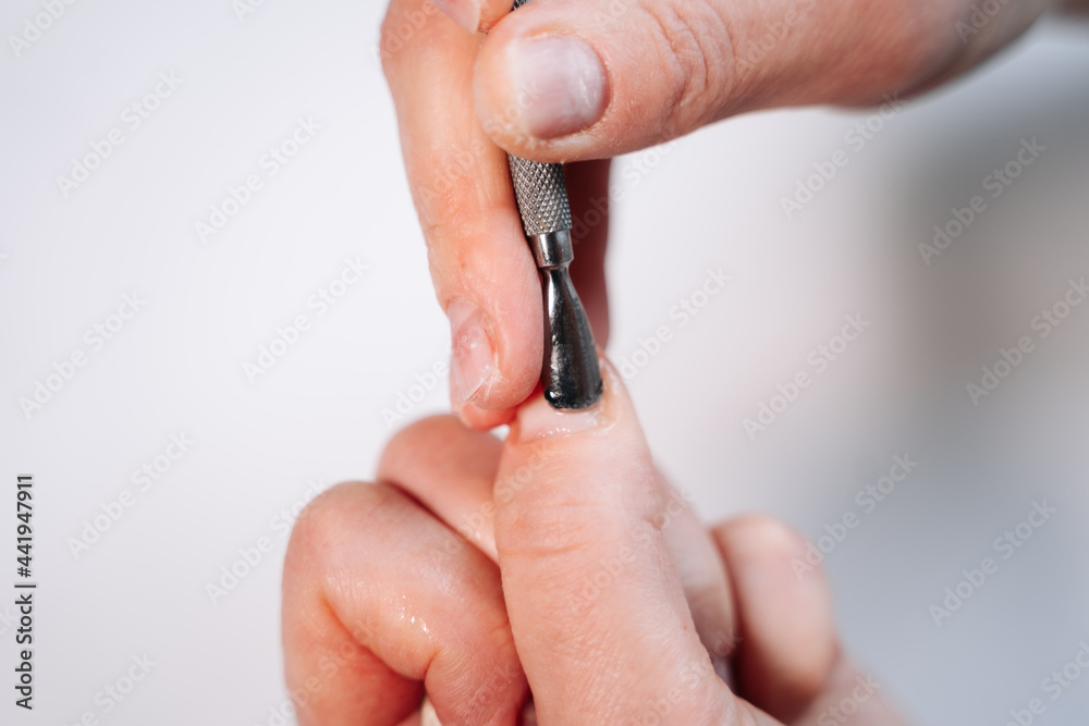 Home manicure. In the photo, a woman is using a cuticle lifting tool. Close-up view. Home manicure. In the photo, a woman is using a cuticle lifting tool. Close-up view.