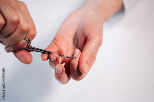 Home manicure. In the photo, a woman cuts off a raised cuticle with manicure scissors. photo