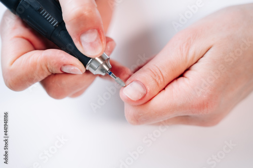 Home manicure. In the photo, a woman removes the top layer of the nail plate using a nail cutter.