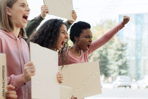 Side view of multiracial ladies with empty placards chanting slogans © Prostock-studio