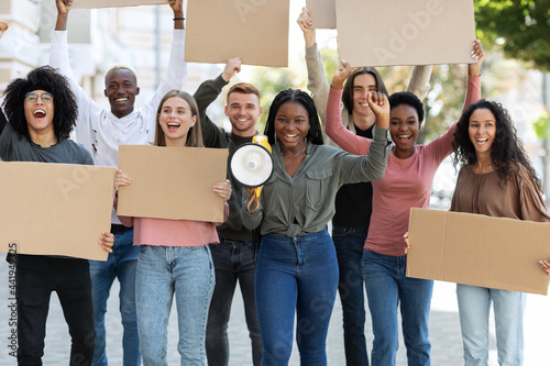 Cheerful multiracial students with blank placards walking by street