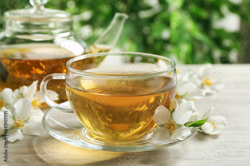 Aromatic jasmine tea and fresh flowers on wooden table, closeup