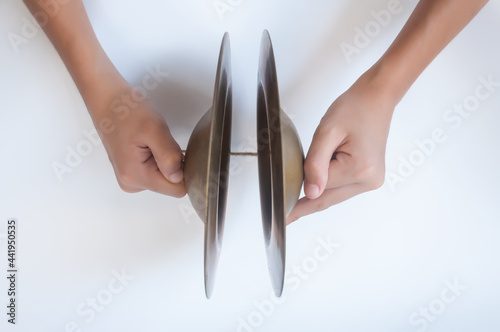 Hand holding cymbals, an old Thai musical instrument isolated on white background.