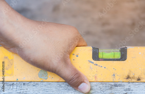 Mechanic's hand using water level meter measuring the wooden floor photo