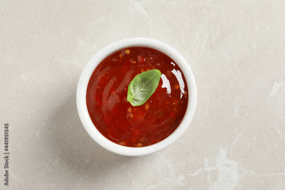 Spicy chili sauce with basil on light table, top view Spicy chili sauce with basil on light table, top view