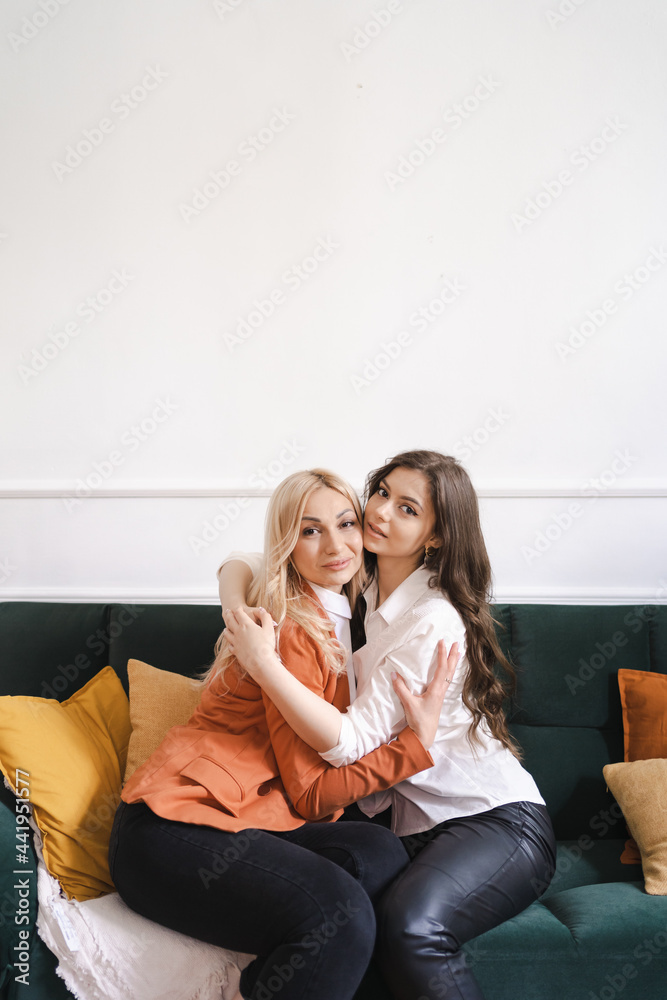 Beautiful mother and adult daughter hugging portrait close up, sitting on couch at home, smiling woman embracing mum, spending leisure time together, two generations good relationship Beautiful mother and adult daughter hugging portrait close up, sitting on couch at home, smiling woman embracing mum, spending leisure time together, two generations good relationship