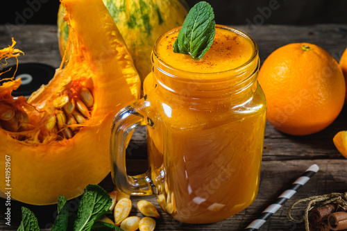 Pumpkin smoothies with mint leaves with a piece or pieces of raw pumpkin and orange in jar photo
