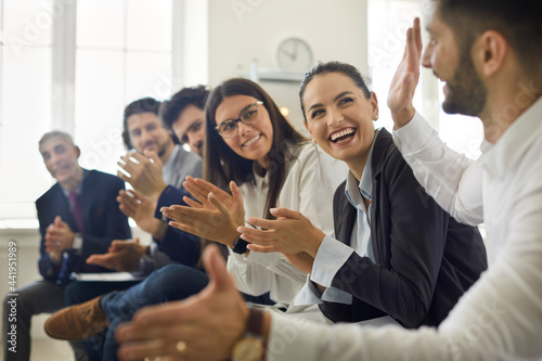 Group of people thanking speaker for interesting presentation in professional business conference or seminar. Team of happy male and female company workers applauding colleague in corporate meeting photo