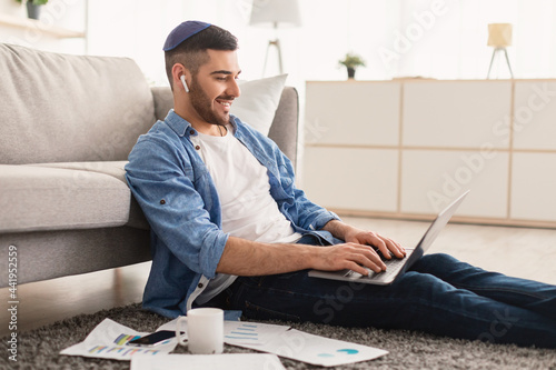 Smiling male jew working on laptop at home photo