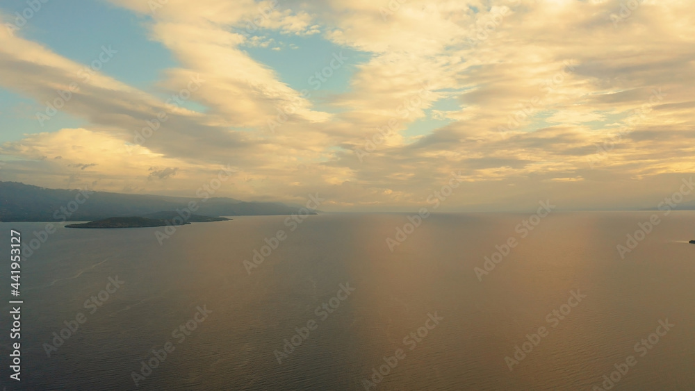 Sunset above the sea surface with waves, top view. Reflected sun on a water surface. Sunset over ocean. Seascape, Summer and travel vacation concept