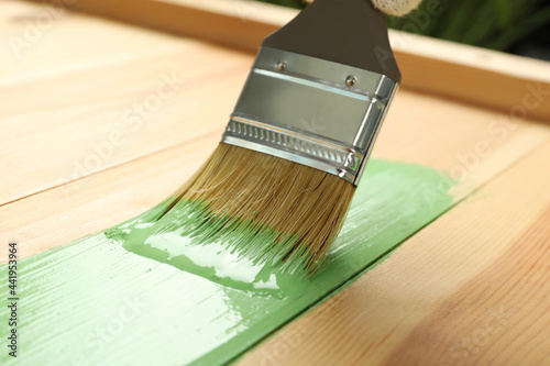 Fototapeta Naklejka Na Ścianę i Meble -  Applying green paint onto wooden surface, closeup