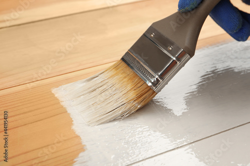 Fototapeta Naklejka Na Ścianę i Meble -  Worker applying white paint onto wooden surface, closeup