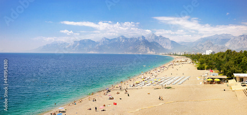 Fototapeta Naklejka Na Ścianę i Meble -  Wonderful mediterranean resort landscape of calm turquoise sea, wide beach line, green parks, mountains on horizon with white clouds and bright blue skies.