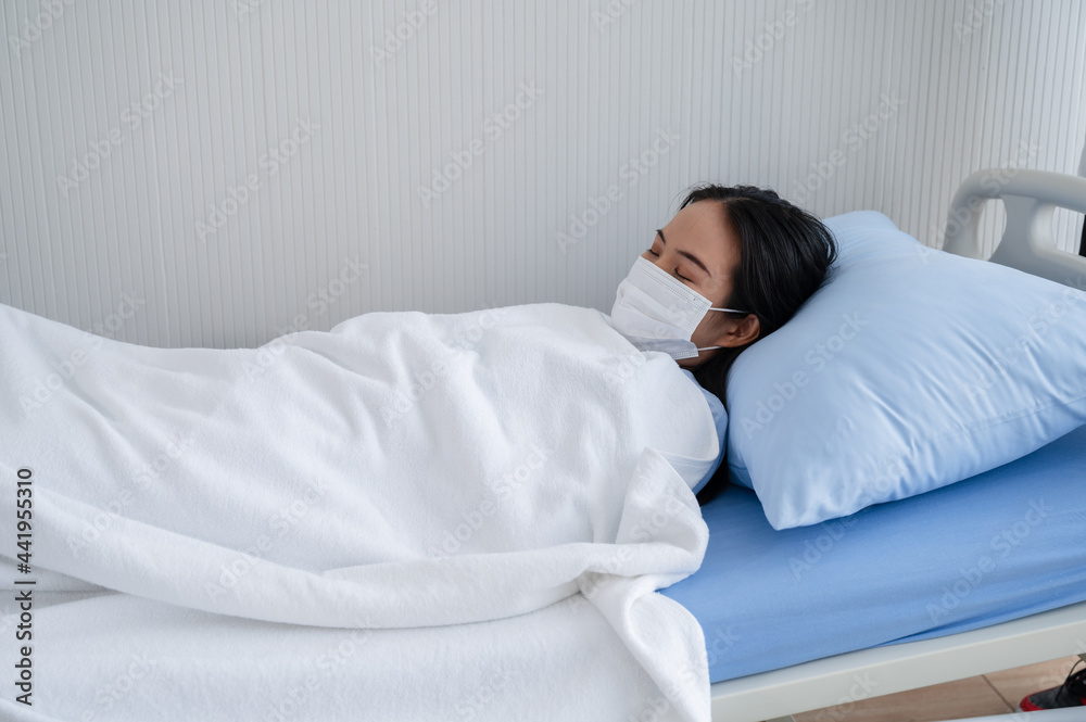 Yong woman sleeping wearing a mask in hospital bed to check herself during coronavirus 19 virus outbreak. Concepts to prevent the spread of COVID-19. Yong woman sleeping wearing a mask in hospital bed to check herself during coronavirus 19 virus outbreak. Concepts to prevent the spread of COVID-19.