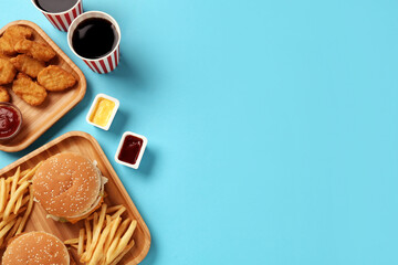 Different fast food on turquoise background, flat lay. Space for text