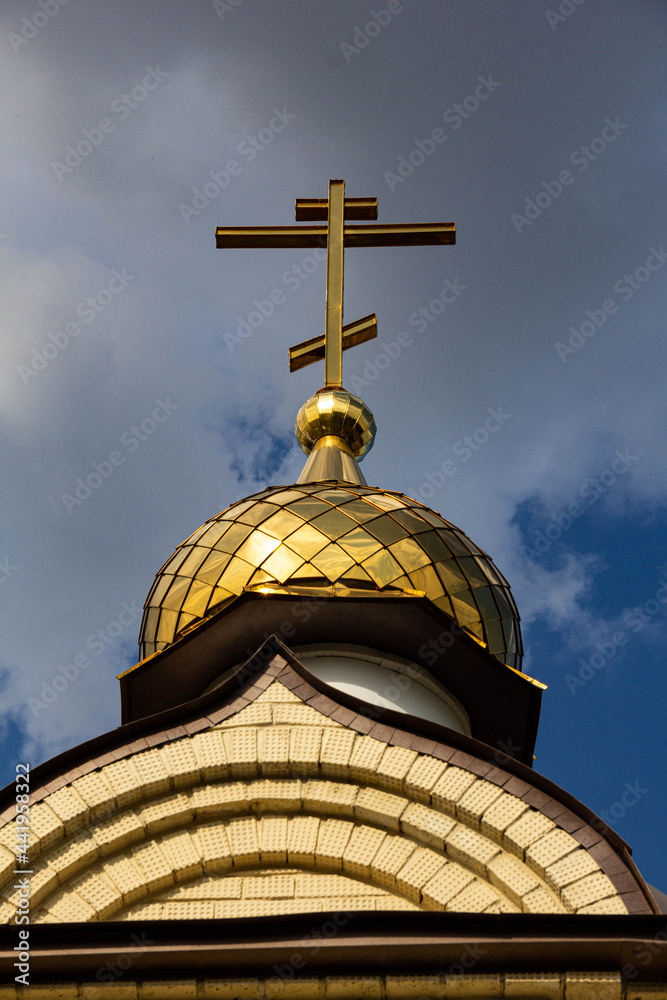 The roof of the Orthodox church with a golden dome and a cross against the sky.