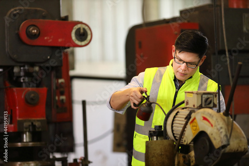 Fotografie Asian engineer is lubricating the heavy machine for maintenance service inside t