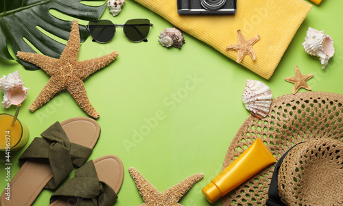 Frame of different beach objects on green background, flat lay. Space for text