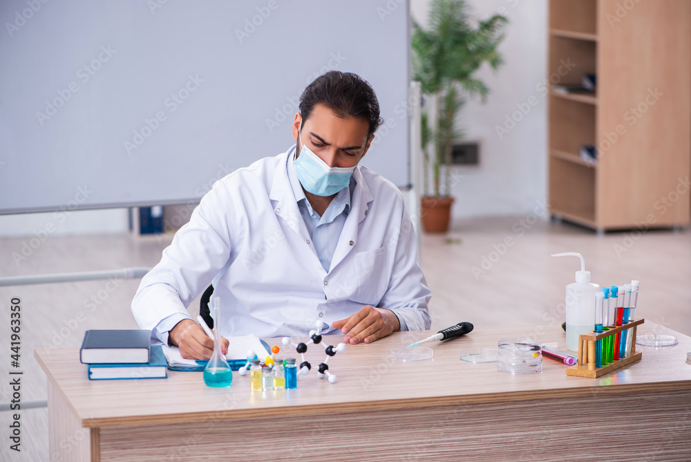 Fototapeta premium Young male chemist teacher sitting in the classroom