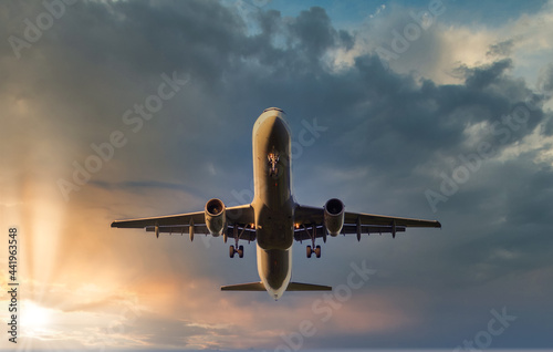 Airplane landing during sunset at airport with clouds in background, view from low angle