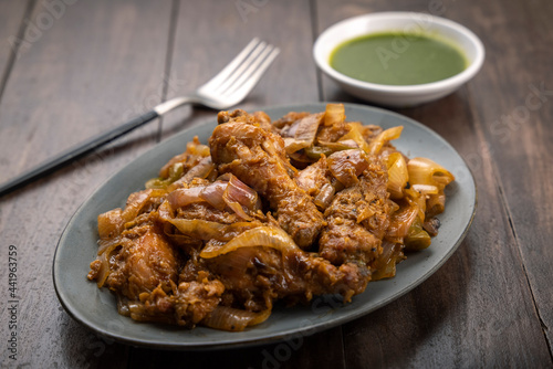 Chilli chicken is a popular Indo-Chinese dish, served on a plate on wooden background 