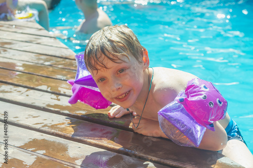 Foto A wet boy gets out of the pool water after swimming on a hot summer day