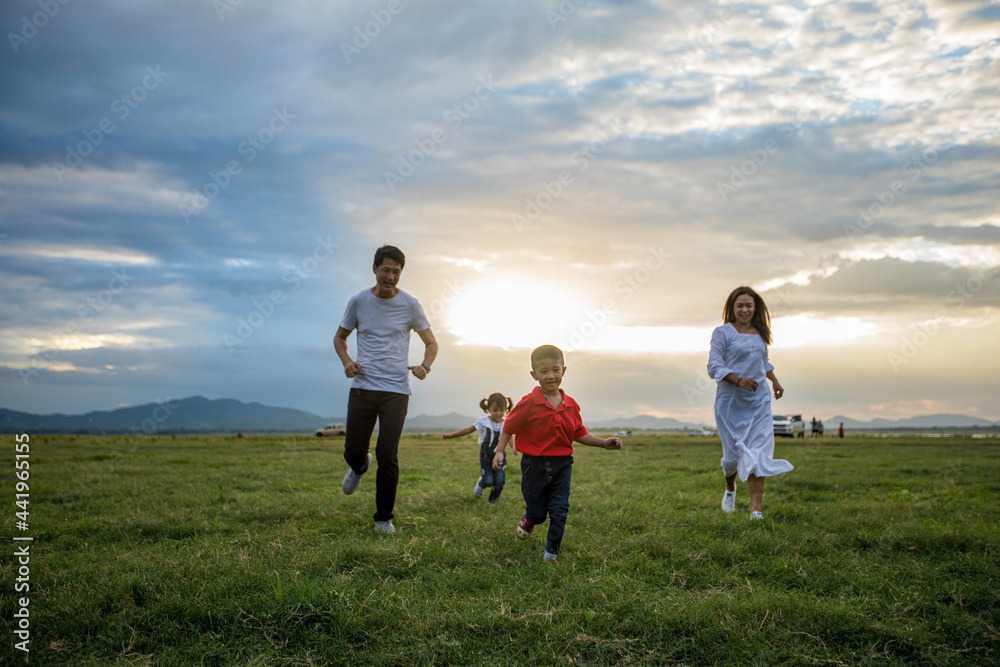 Asian family walking and running on the Meadow at sunset with happy emotion. Family, Holiday and Travel concept. Asian family walking and running on the Meadow at sunset with happy emotion. Family, Holiday and Travel concept.