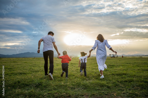 Asian family walking and running on the Meadow at sunset with happy emotion. Family, Holiday and Travel concept.