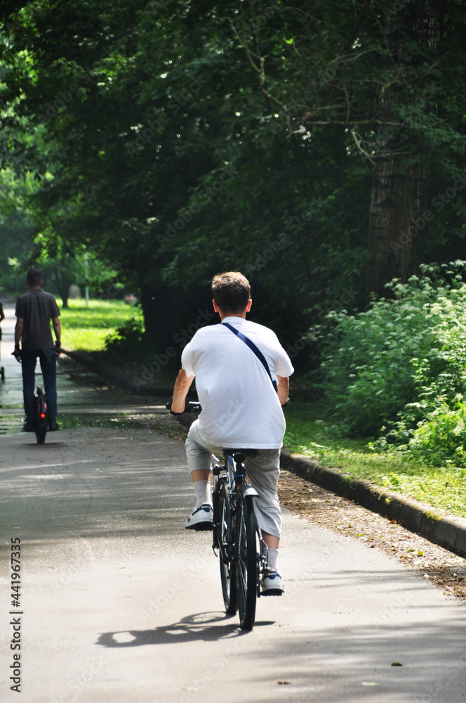Obraz premium Sports activities in the park. A man rides a bicycle along the park alley. Healthy lifestyle.
