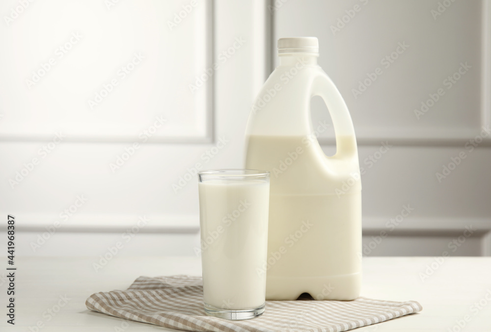 Gallon bottle and glass of milk on white wooden table Gallon bottle and glass of milk on white wooden table