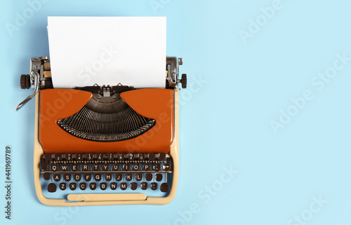Vintage typewriter on light blue background, top view. Space for text