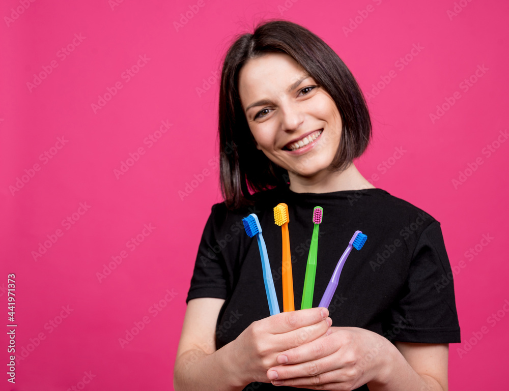 Beautiful happy young woman with different colored toothbrushes on blank pink background Beautiful happy young woman with different colored toothbrushes on blank pink background