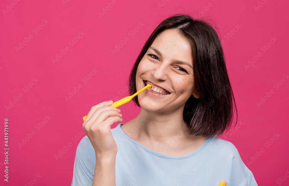 Beautiful happy young woman with single tufted toothbrush on blank pink background Beautiful happy young woman with single tufted toothbrush on blank pink background